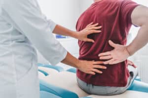 Cropped close up of female orthopedist examining patient's back in clinic