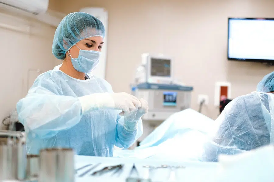 Surgeon wearing a blue dress and latex gloves inside the operating room 