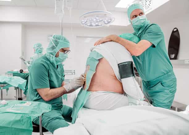 Male surgeons preparing a patient for a spinal fusion surgery 