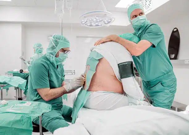 Male surgeons preparing a patient for a spinal fusion surgery 