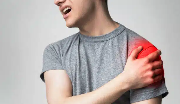 Man holding his shoulder cause of intense pain 