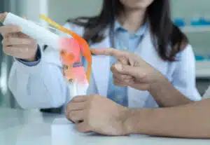 Doctor explain knee pain with model to patient.