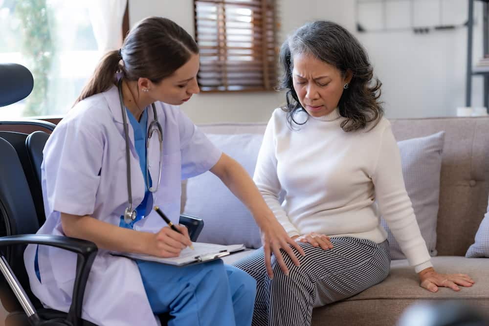 A surgeon examining the knee of an elderly woman patient.