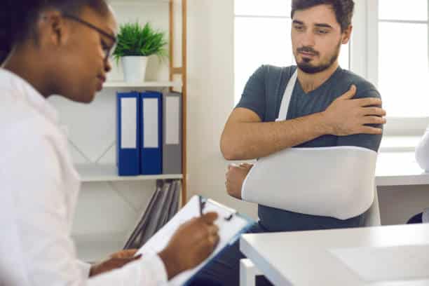 Male patient having a check up with a surgeon after the shoulder surgery.