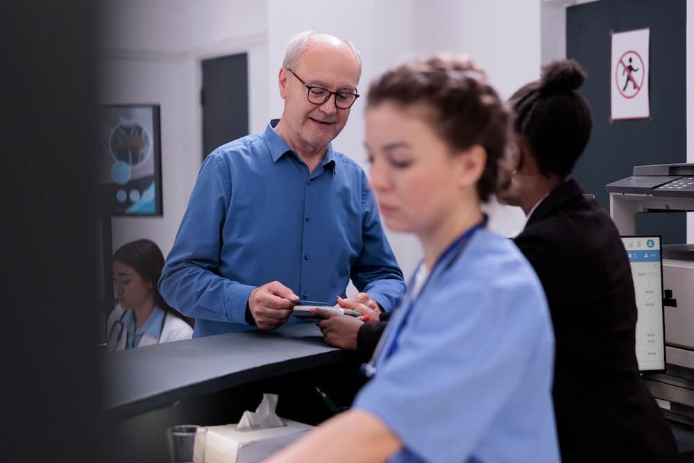 Senior Patient paying his surgery treatment with own debit card.