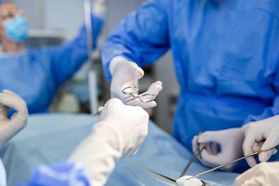 Doctor and nurse medical team performing a surgical operation at an emergency room hospital showing assistant handing out surgical scissors during operation