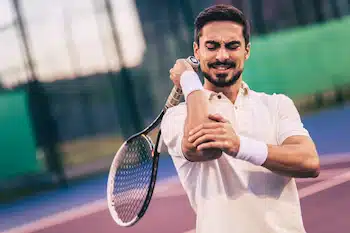 Tennis player with lateral epicondylitis holding his elbow in pain